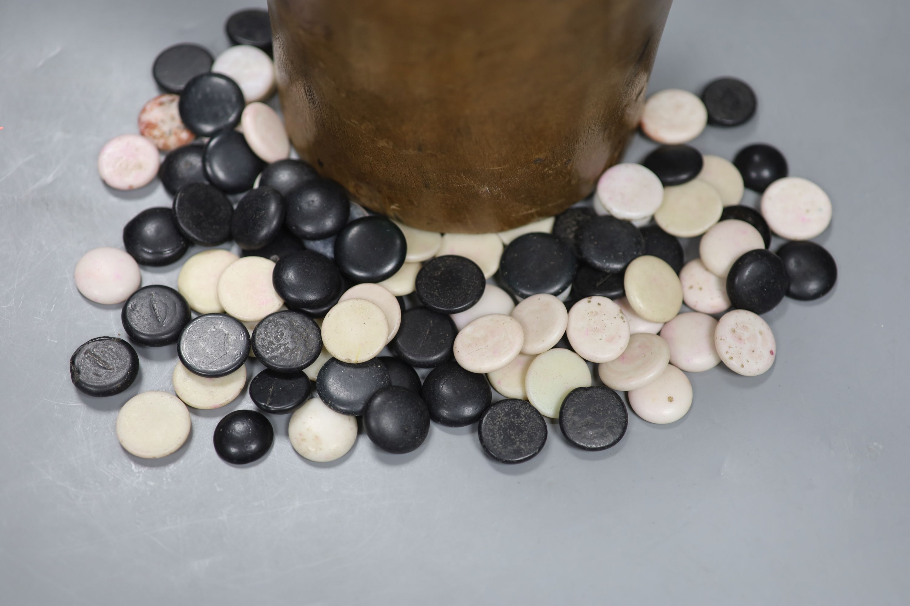 A collection of stone weiqi counters, Ming-Qing dynasty, contained in a nanmu brushpot